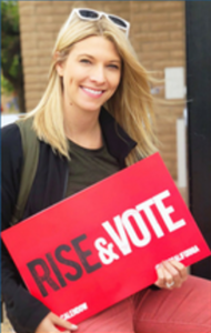Photo Id: Heather Walker Janz holding a sign that says "Rise & Vote"
