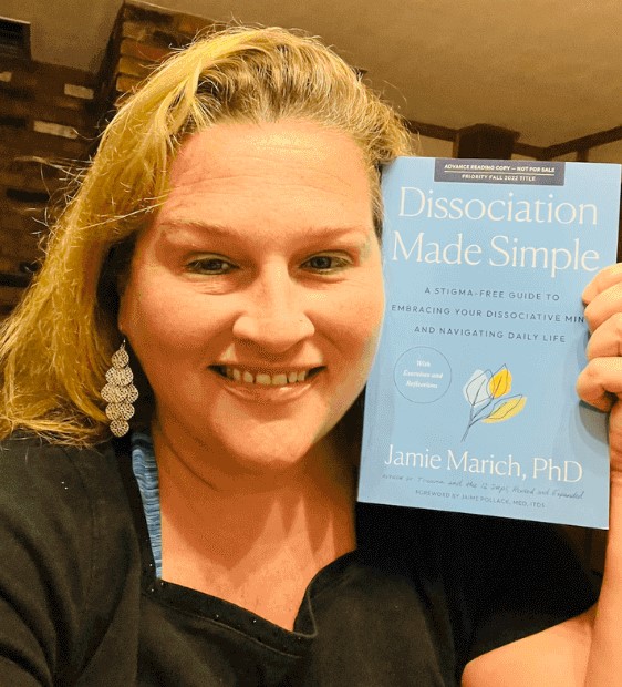 Photo ID: Dr. Jamie Marich holding her new book "Dissociation Made Simple"