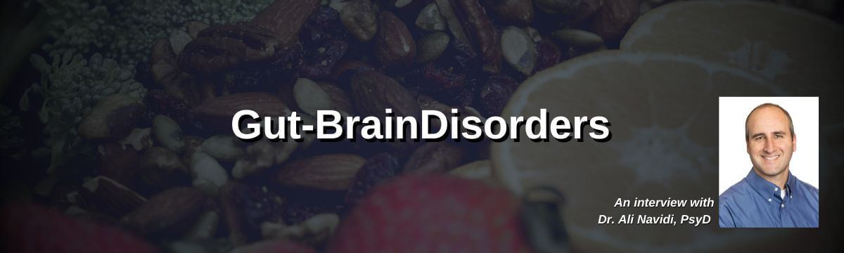 Image: Background shows assorted healthy foods including strawberries, nuts, broccoli, and sliced citrus fruit. Text reads: “Gut-Brain Disorders.” A headshot of a smiling man in a blue button-down shirt appears in the corner. Text below reads: “An interview with Dr. Ali Navidi, PsyD.”